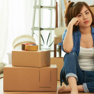 full-shot-tired-woman-sitting-floor-packing-boxes